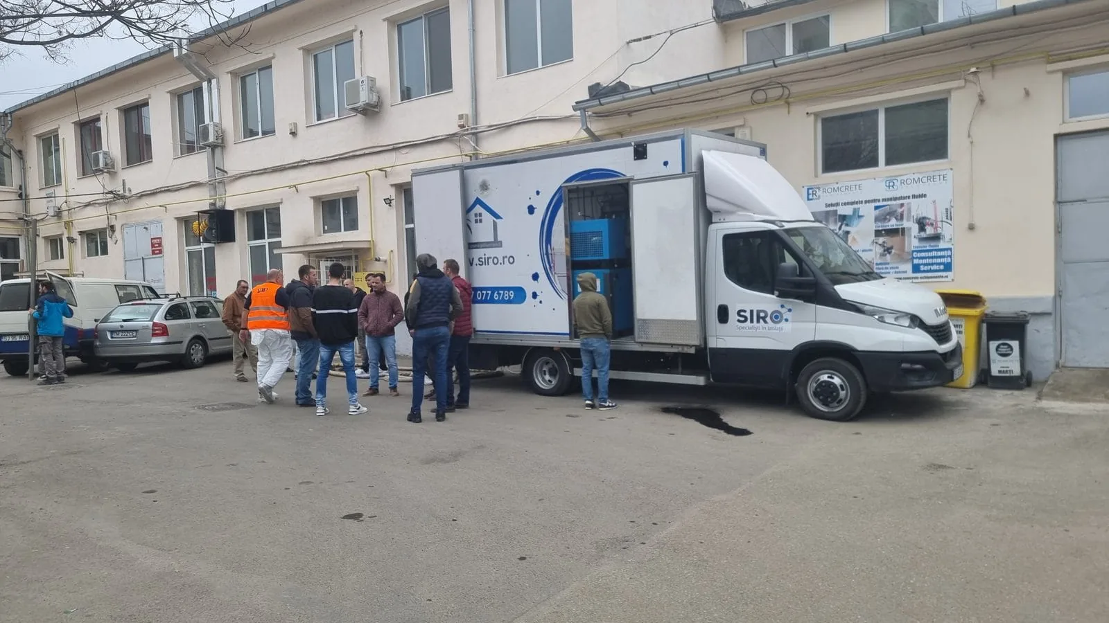 Demonstrație tehnică în fața autoutilitarei, cu participanți urmărind aplicarea