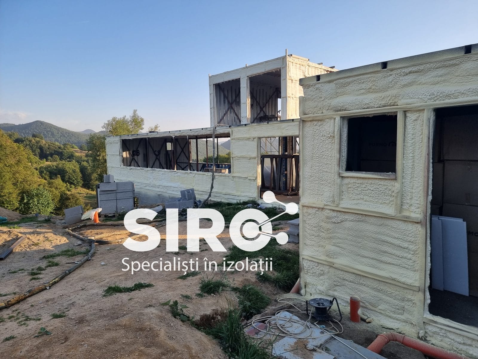 Perete exterior în lucru, cu stratul de spumă aplicat pe zona deja pregătită